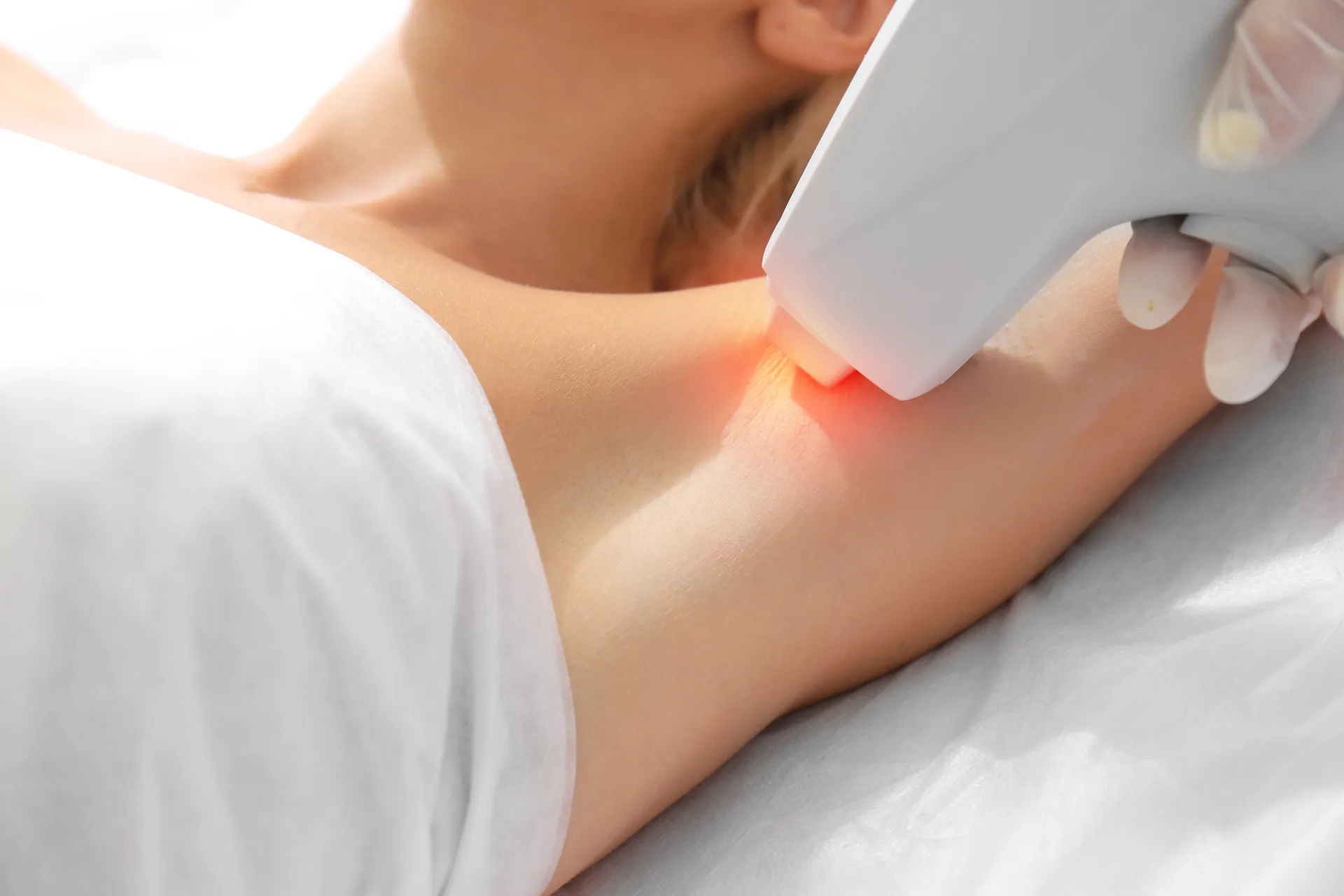 Person receiving laser hair removal treatment on underarm with a handheld device