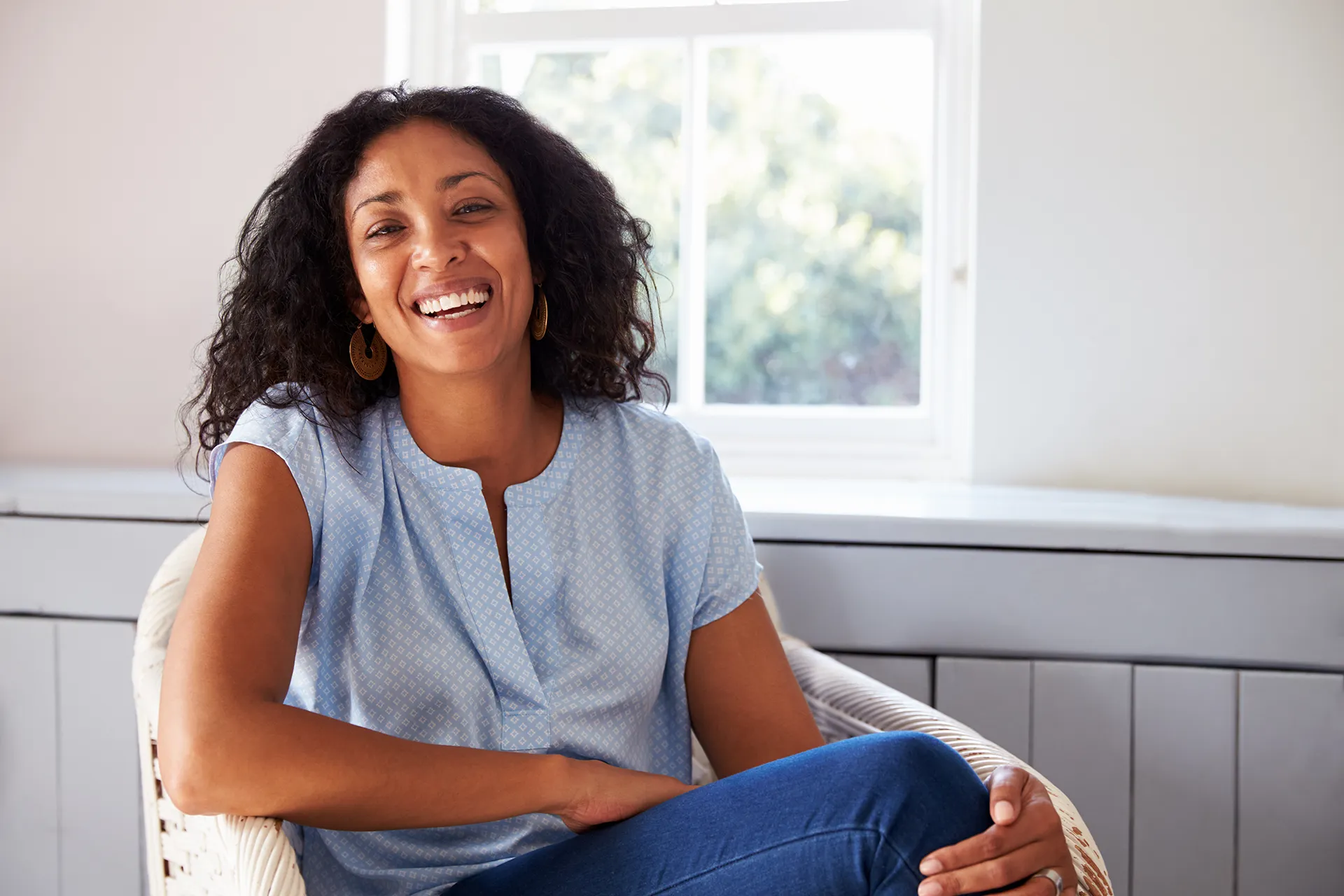 Smiling Woman in Blue Blouse Sitting in a Chair