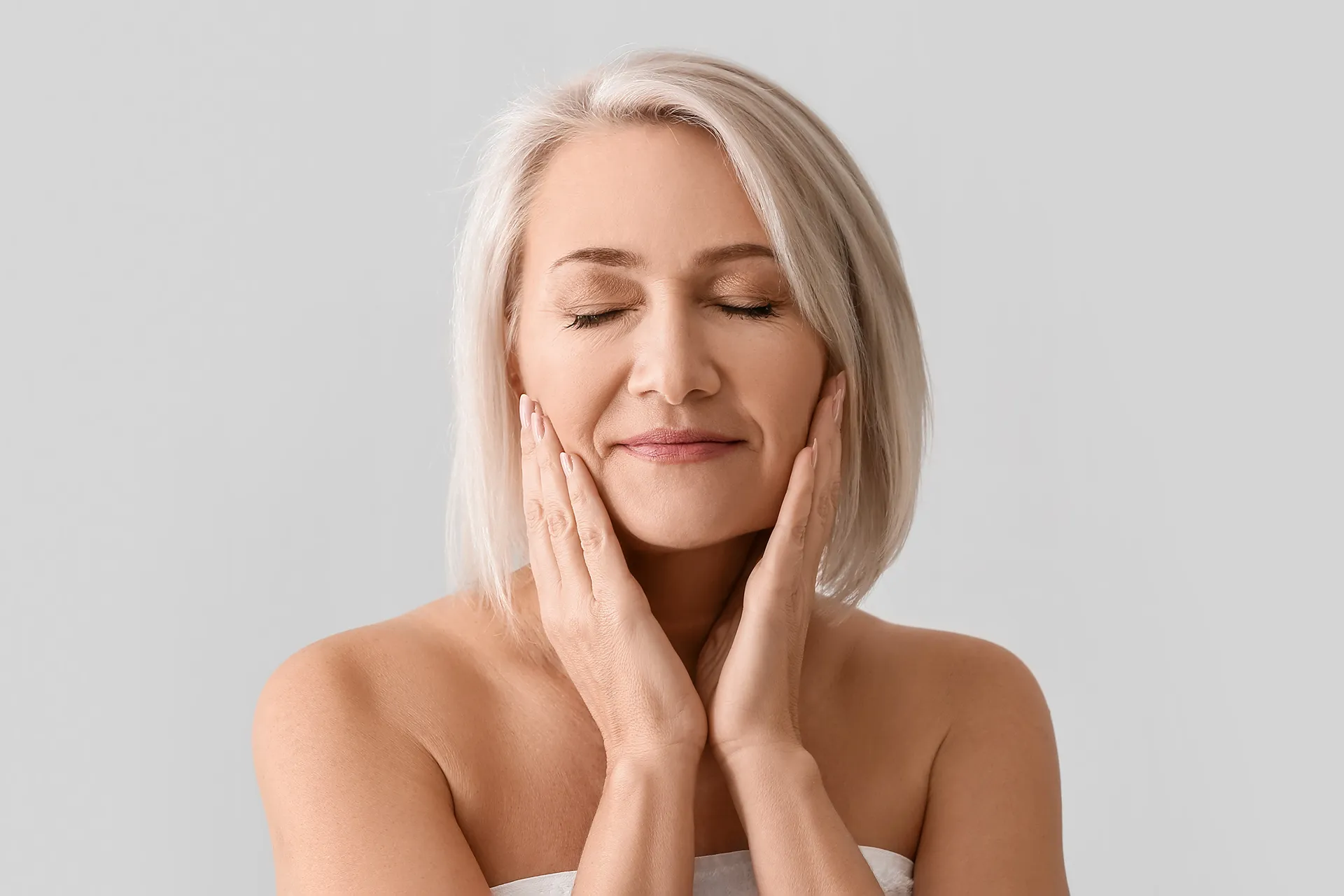 A middle-aged woman gently touching her face.